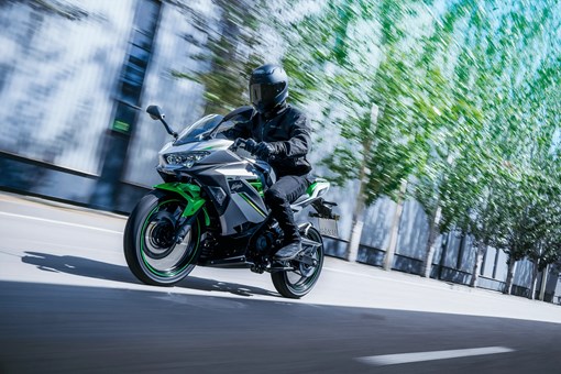 Side angle of a person riding a motorcycle on a street. opens in a new window