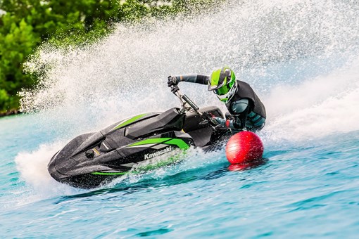 Three-quarter front angle of a person turning with a helmet on a personal watercraft on the water. opens in a new window
