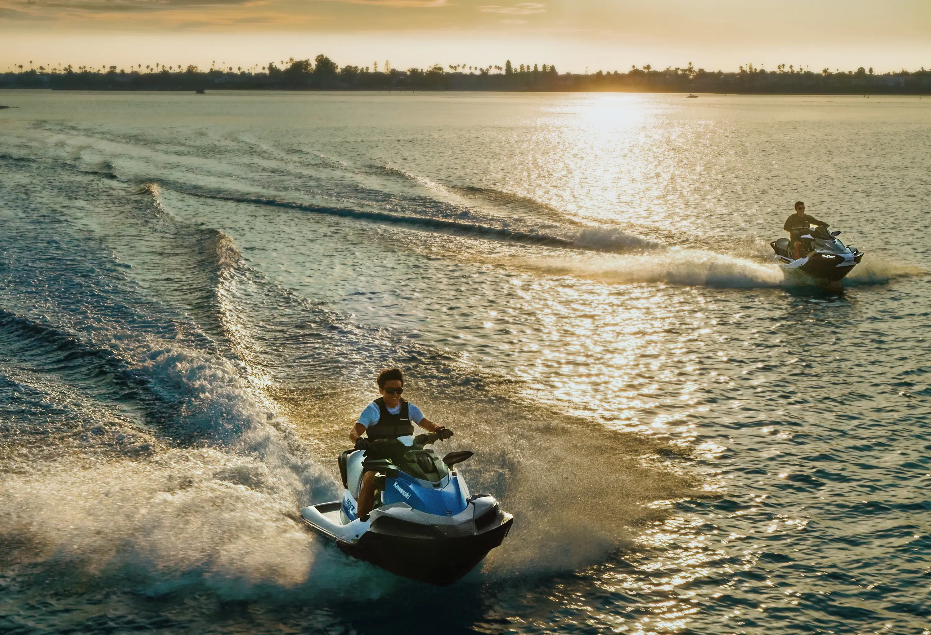 Overhead view of two riders on personal watercraft at sunset.