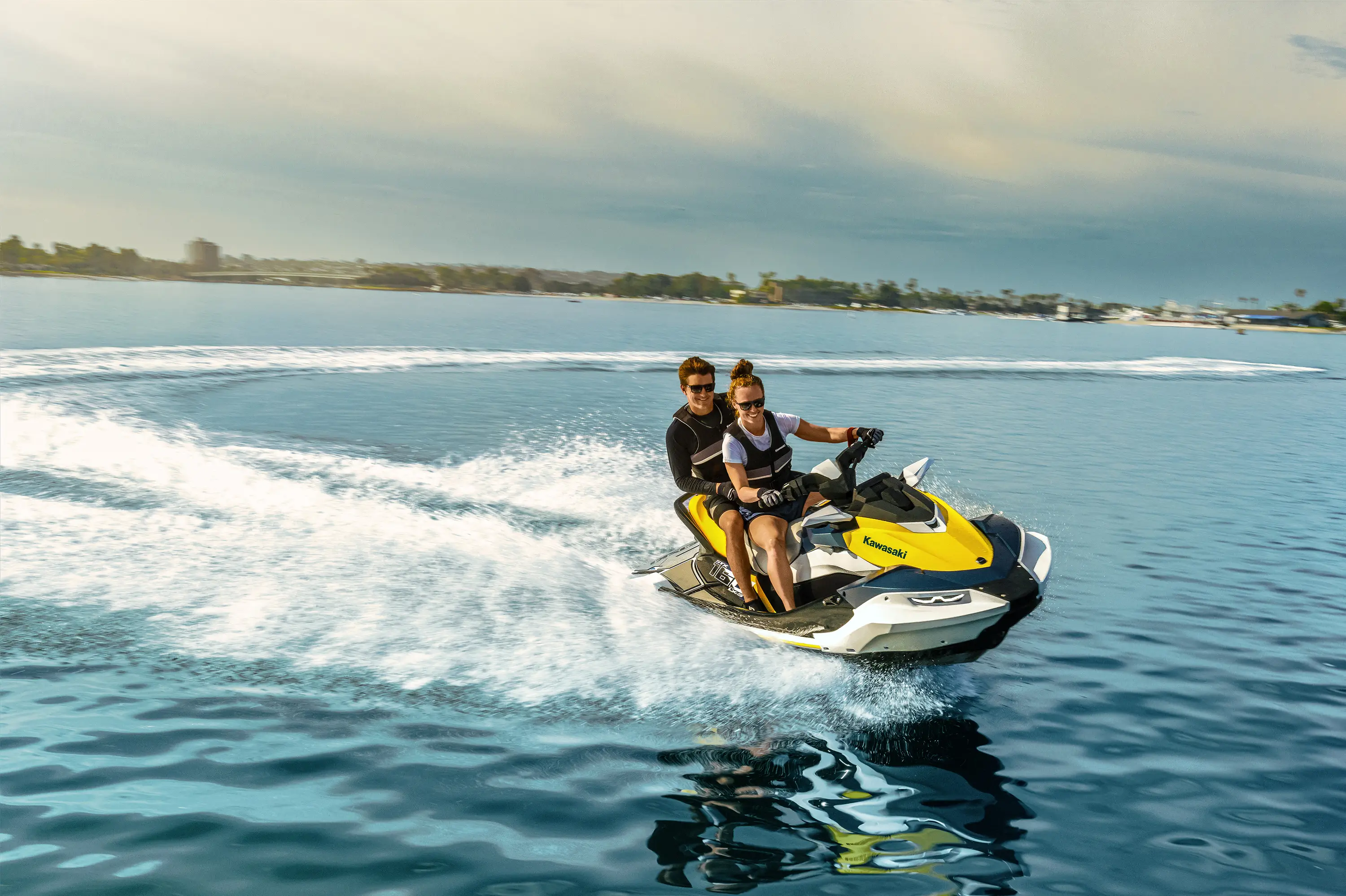 Three-quarter front angle of two people on a personal watercraft on the water.