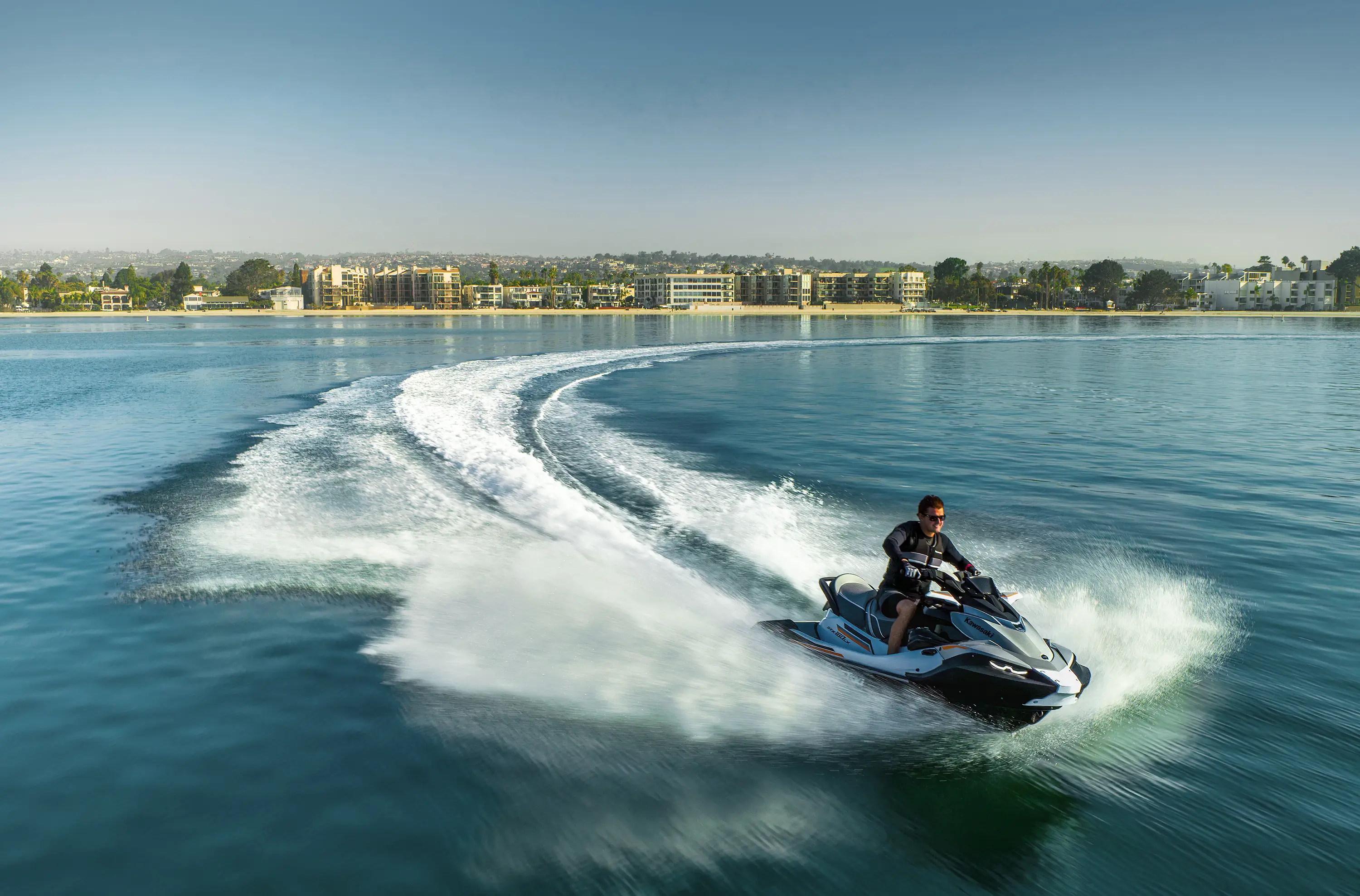 Overhead front angle of a person on a personal watercraft on the water.