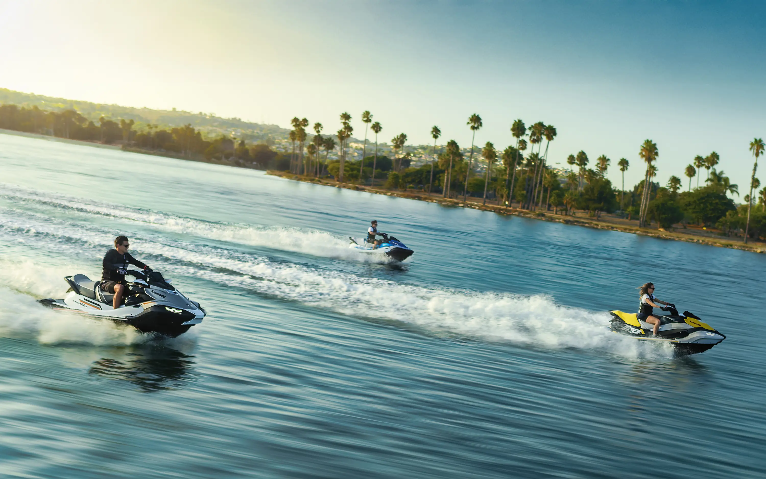 Overhead angle of 3 people on personal watercraft on the water.