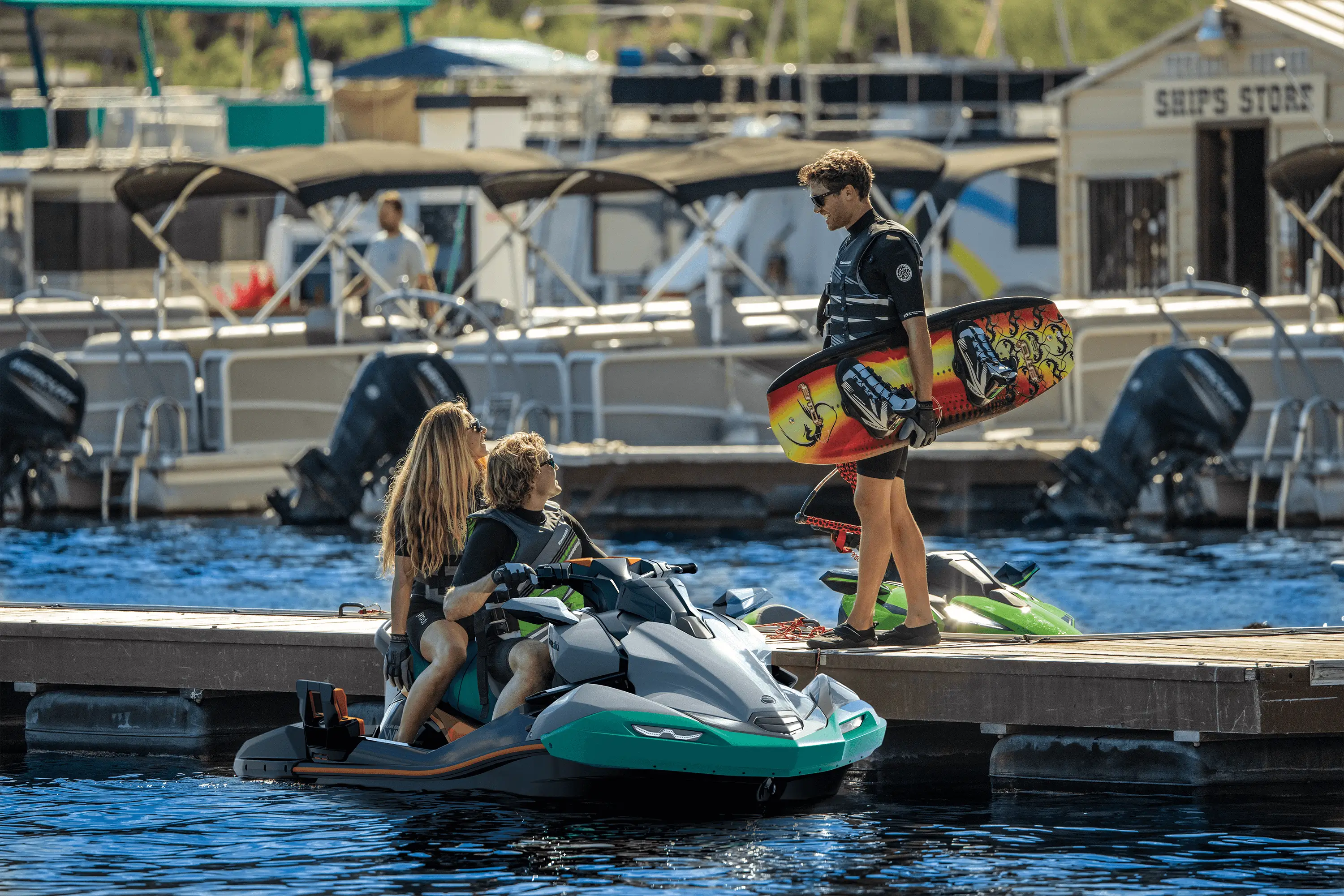 3 people at a dock next to a personal watercraft on the water.