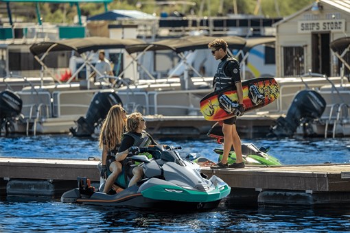 3 people at a dock next to a personal watercraft on the water. opens in a new window