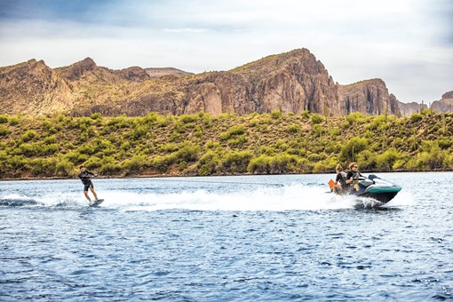 Side angle of a person being towed behind a personal watercraft on a lake. opens in a new window