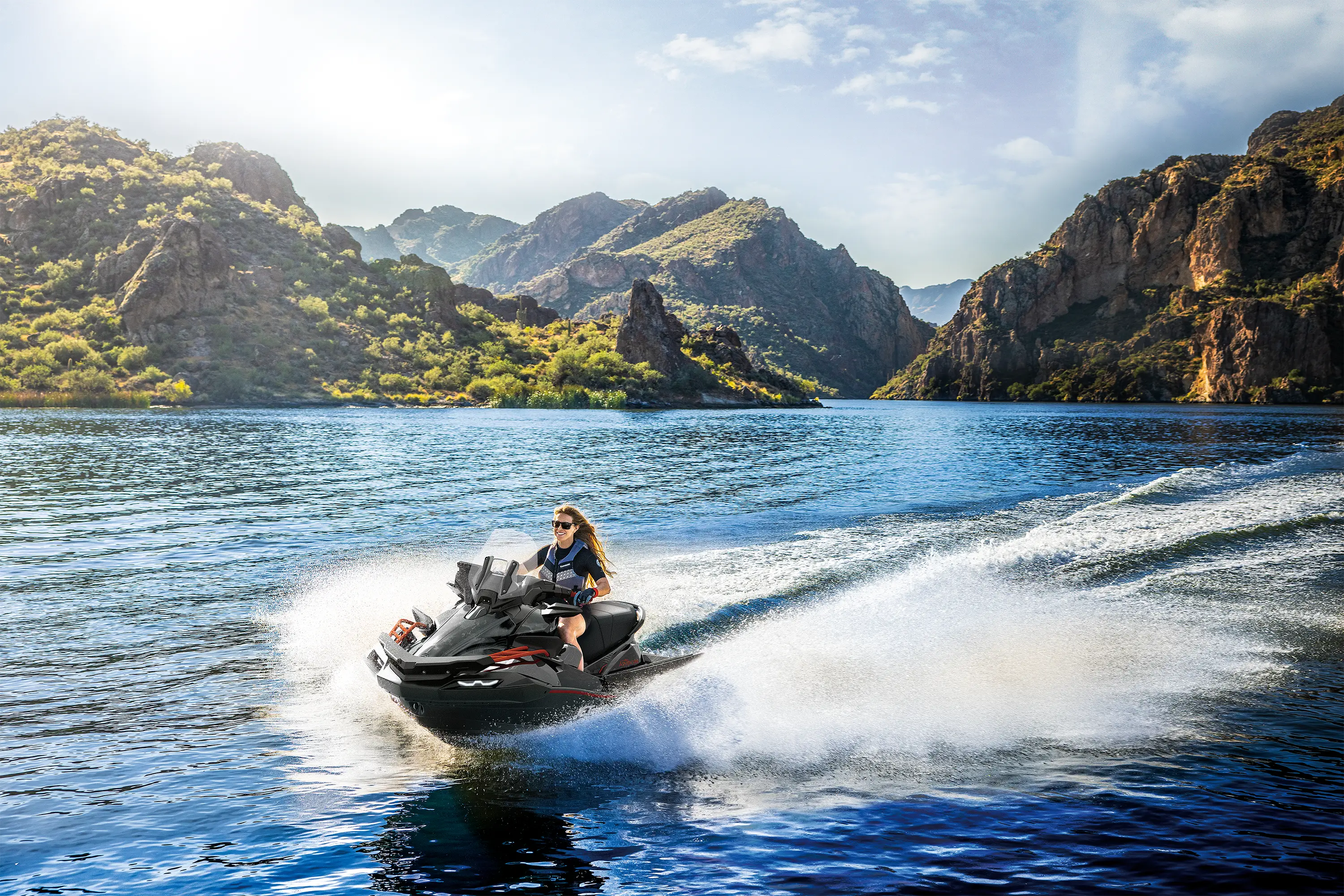Front three-quarter angle of a person on a personal watercraft on the water.
