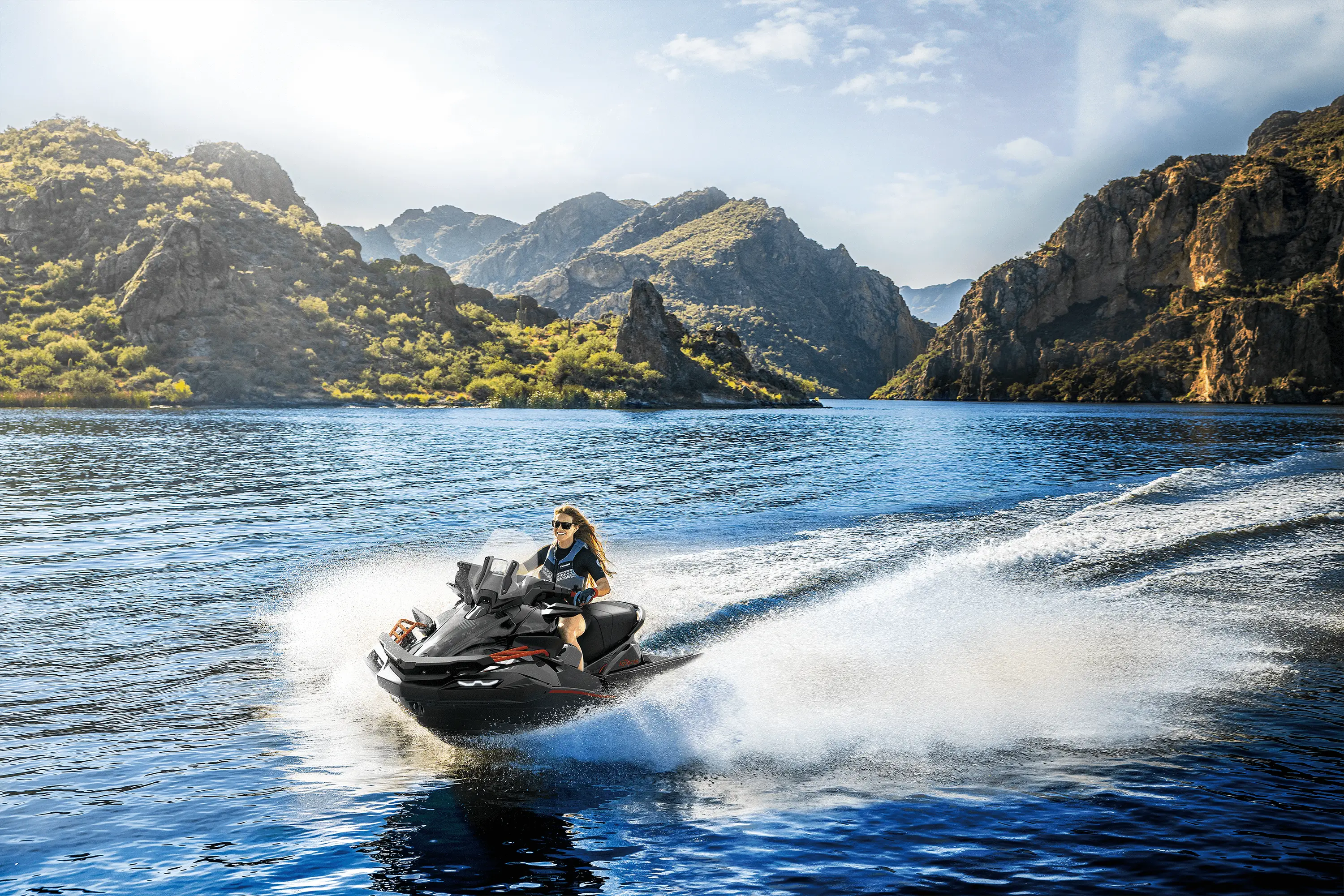 Front three-quarter angle of a person on a personal watercraft on the water.