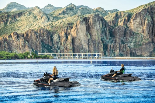 2 people sitting on personal watercraft on the water. opens in a new window
