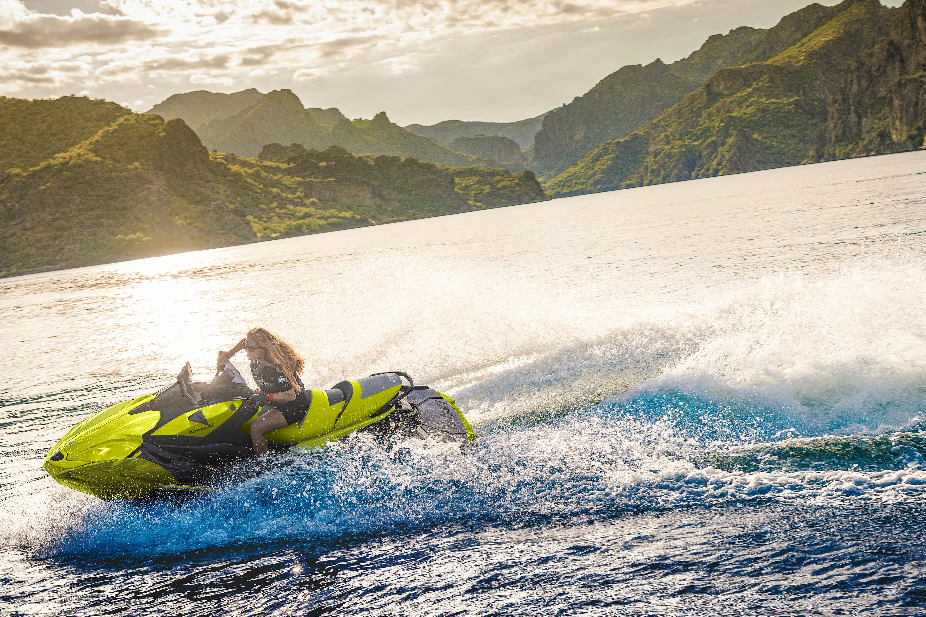 Person turning a personal watercraft on the water at sunset.