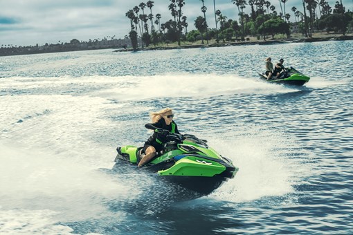 Three-quarter front angle of two people on two personal watercraft on the water. opens in a new window