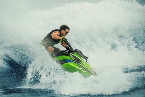 Profile angle of a person in a wave on a personal watercraft on the water. opens in a new window