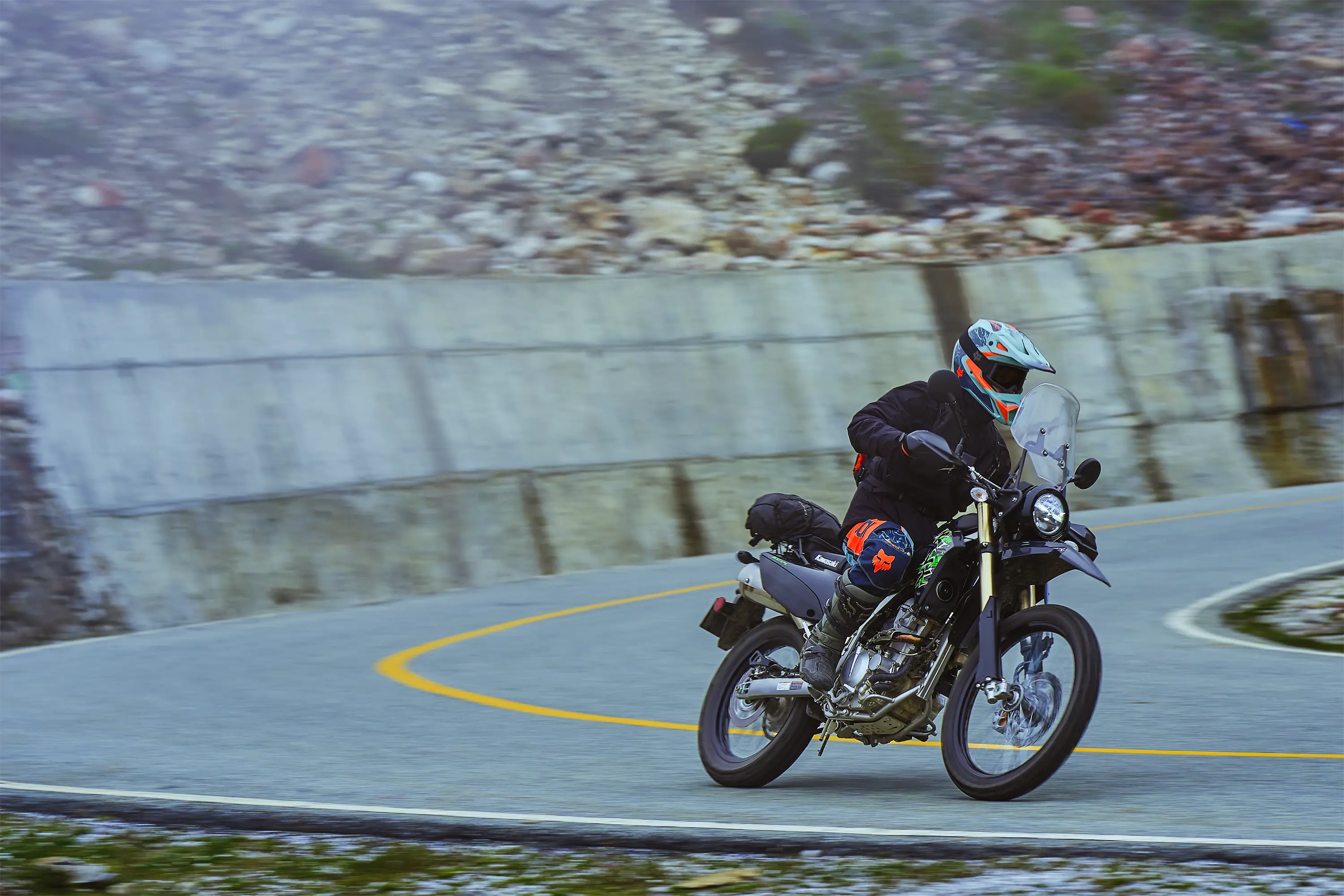 Three-quarter front angle of a person riding a motorcycle on a highway.