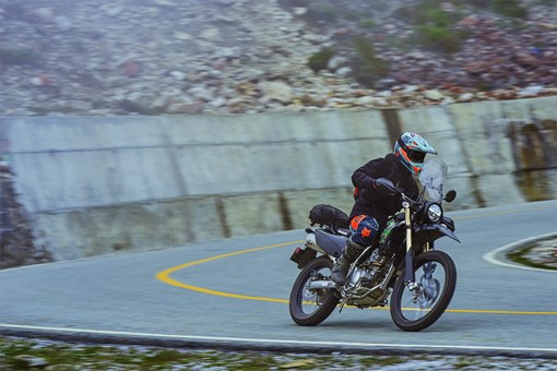 Three-quarter front angle of a person riding a motorcycle on a highway. opens in a new window