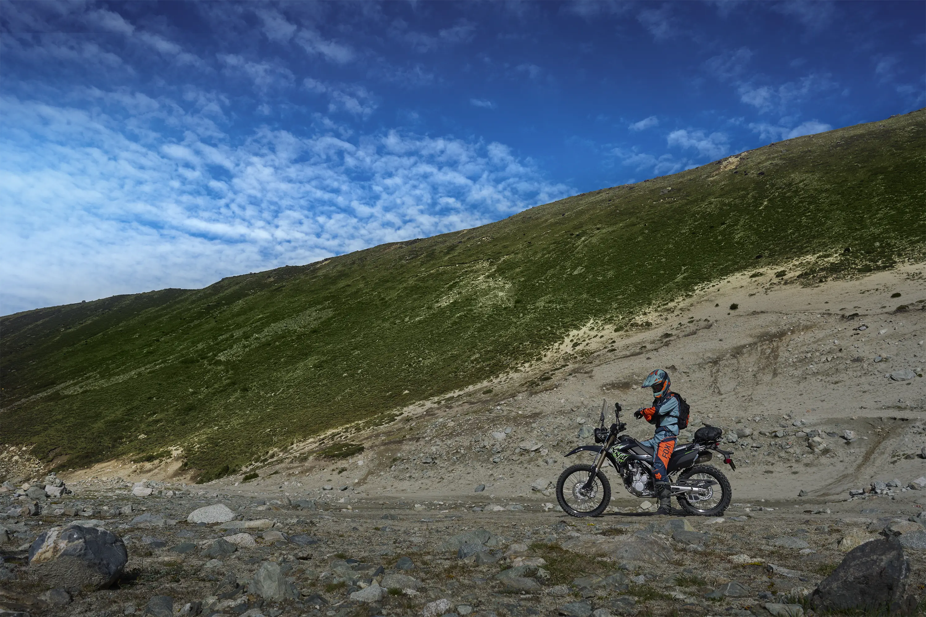 Side angle of a person riding a motorcycle off-road.