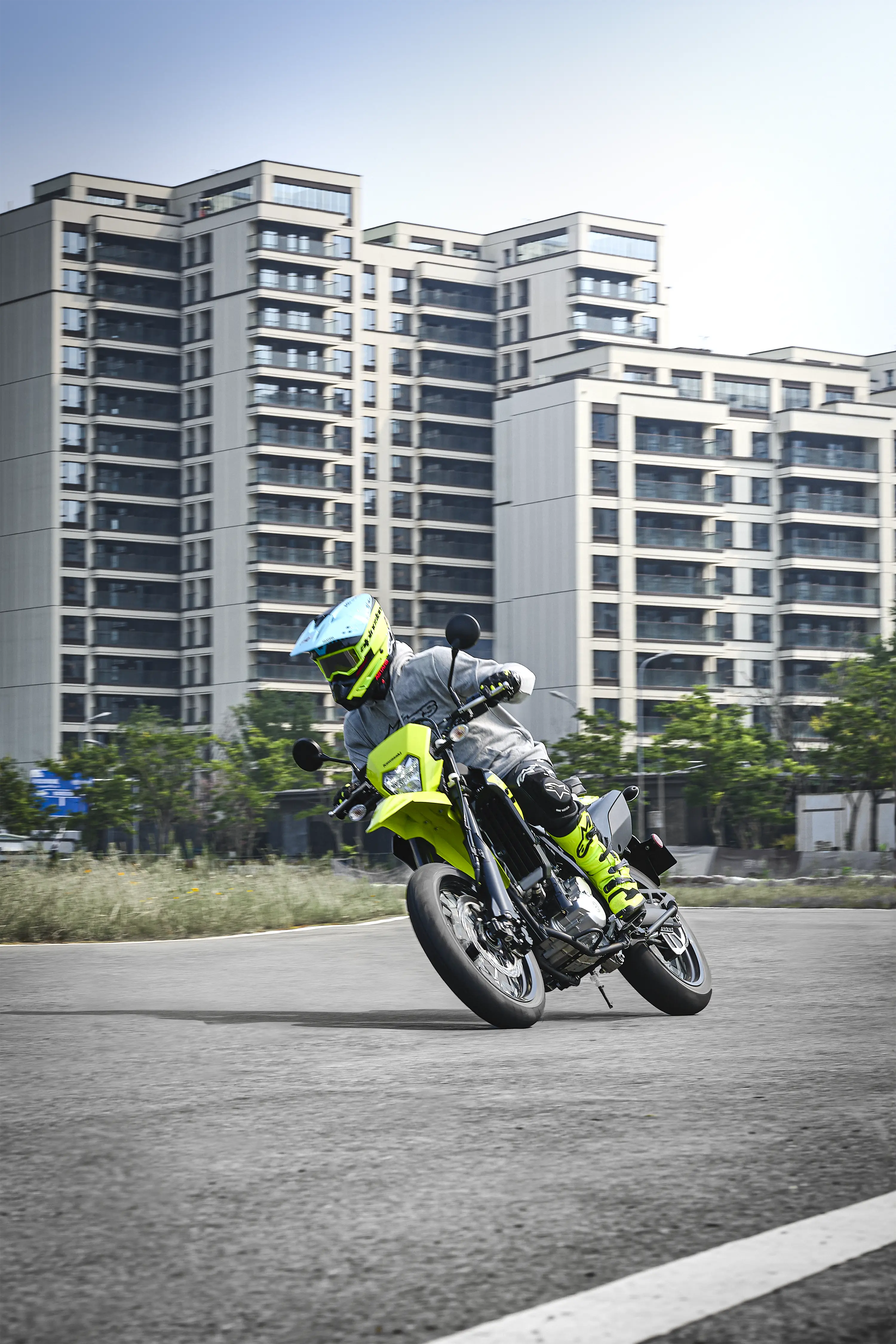 Three-quarter front angle of a person riding a motorcycle on the street.