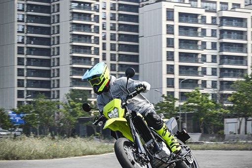 Three-quarter front angle of a person riding a motorcycle on the street. opens in a new window
