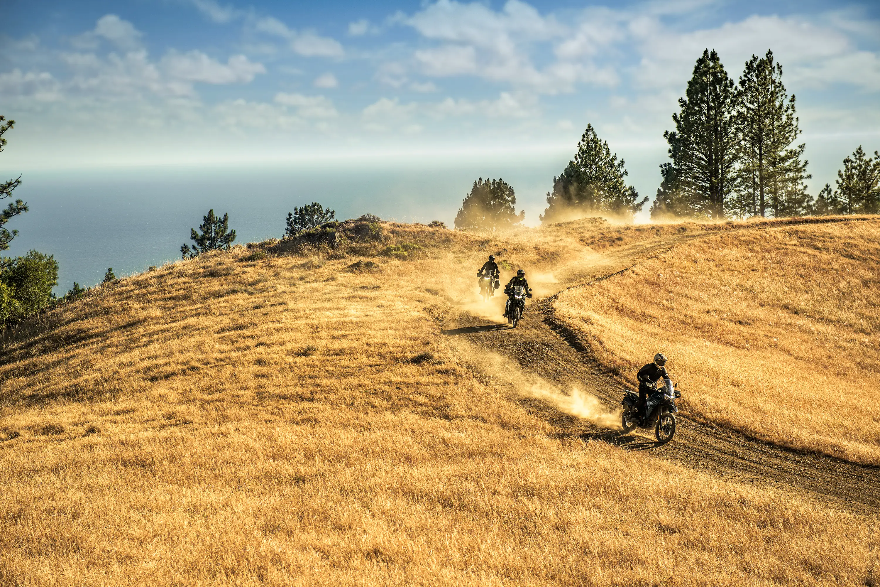 Three-quarter front angle of 3 people riding motorcycles off-road.