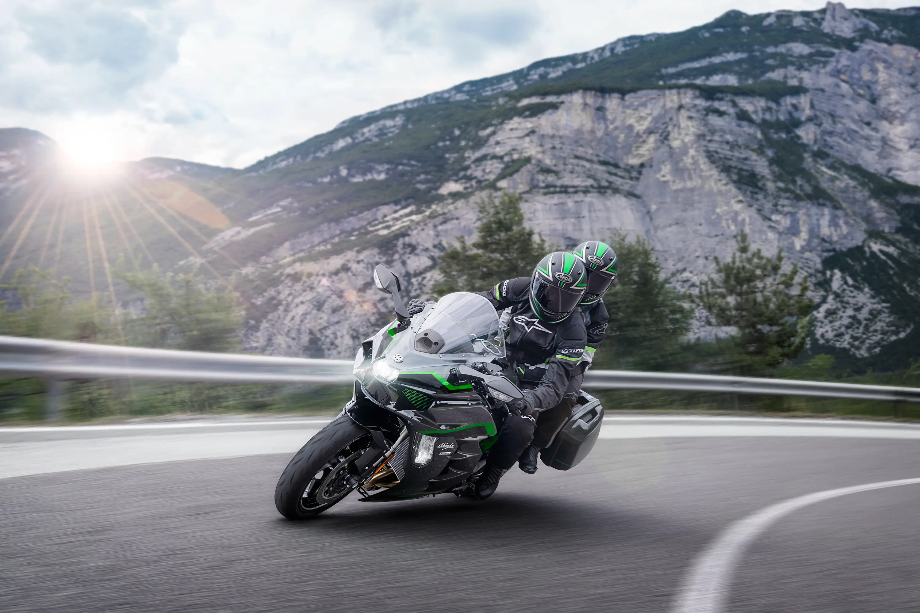 Side angle of two people riding a motorcycle around a curve.