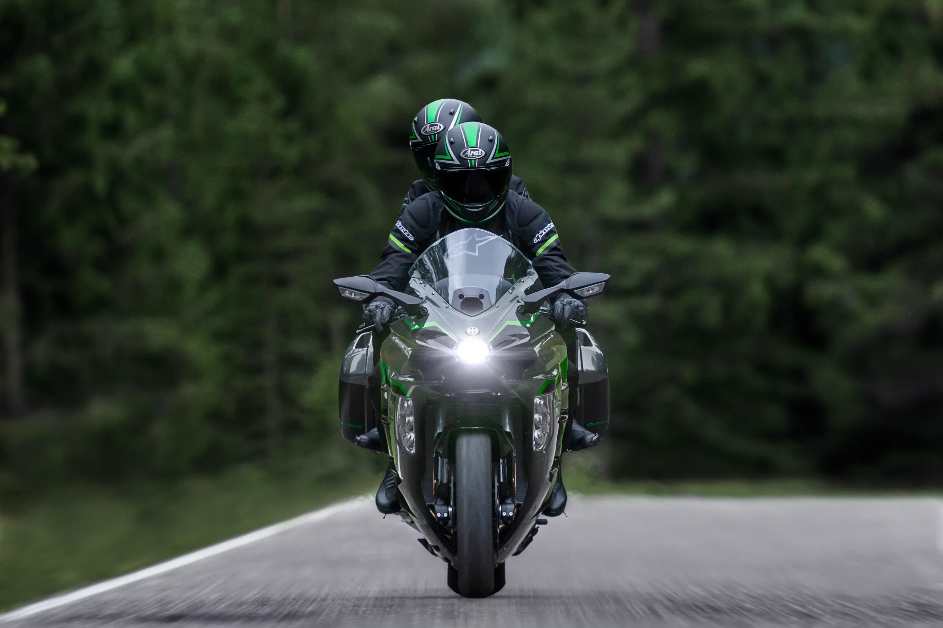 Front angle of two people riding a motorcycle on a highway.