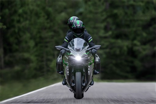 Front angle of two people riding a motorcycle on a highway. opens in a new window