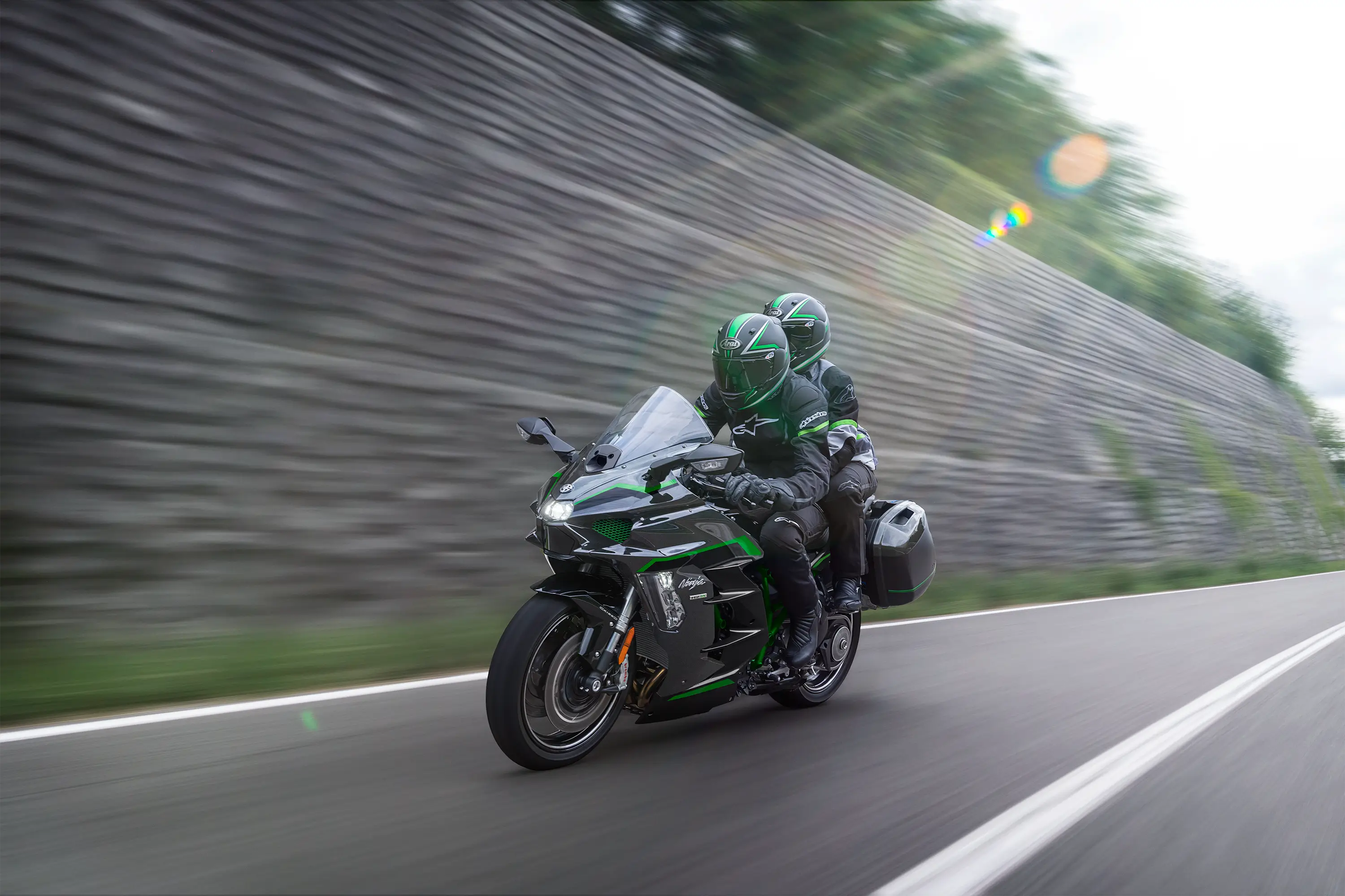Side angle of two people riding a motorcycle on a highway.
