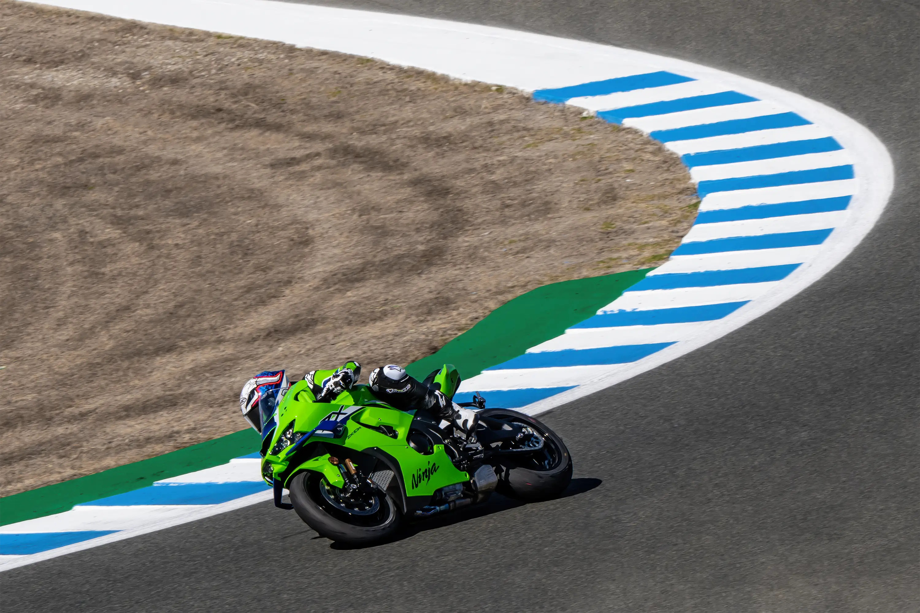 Side angle of a person riding a motorcycle turning on a racetrack.