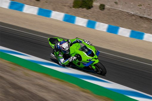 front angle of a person riding a motorcycle turning on a racetrack. opens in a new window