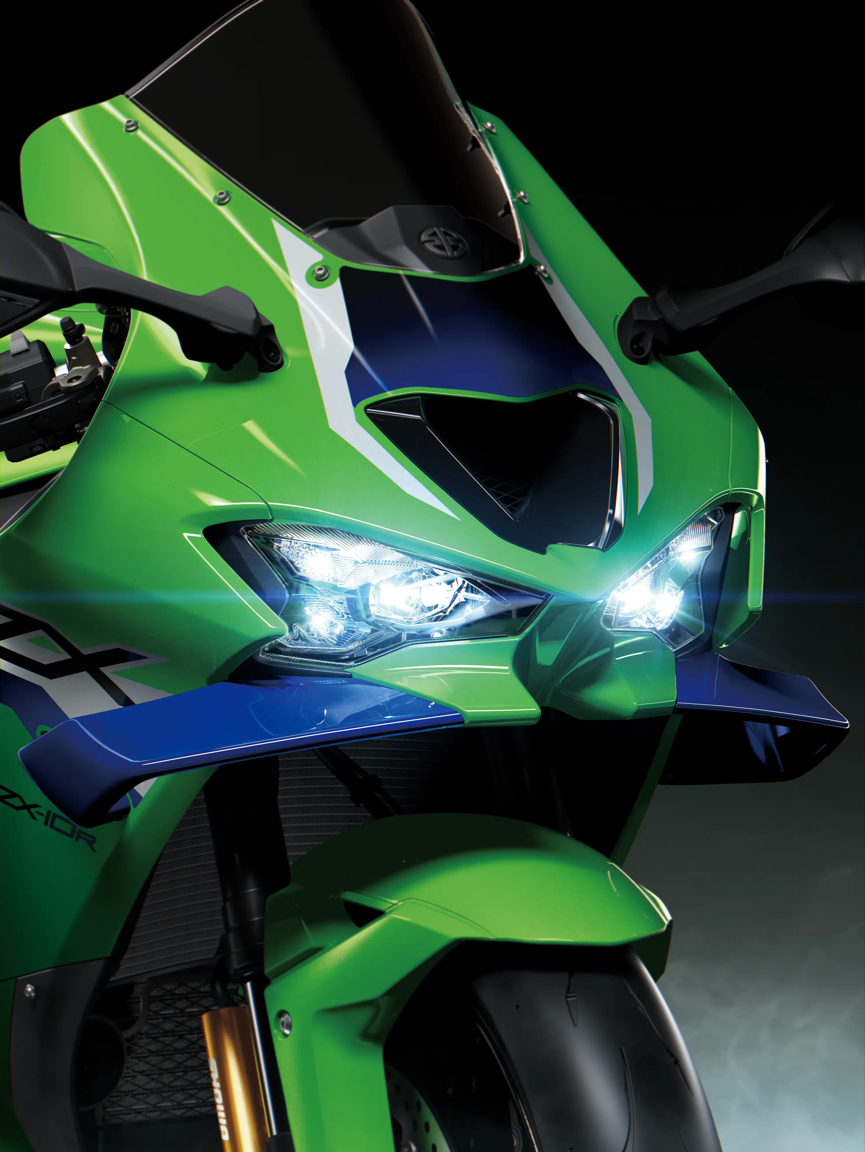Close-up of the front-end of a motorcycle staged in a black studio background.
