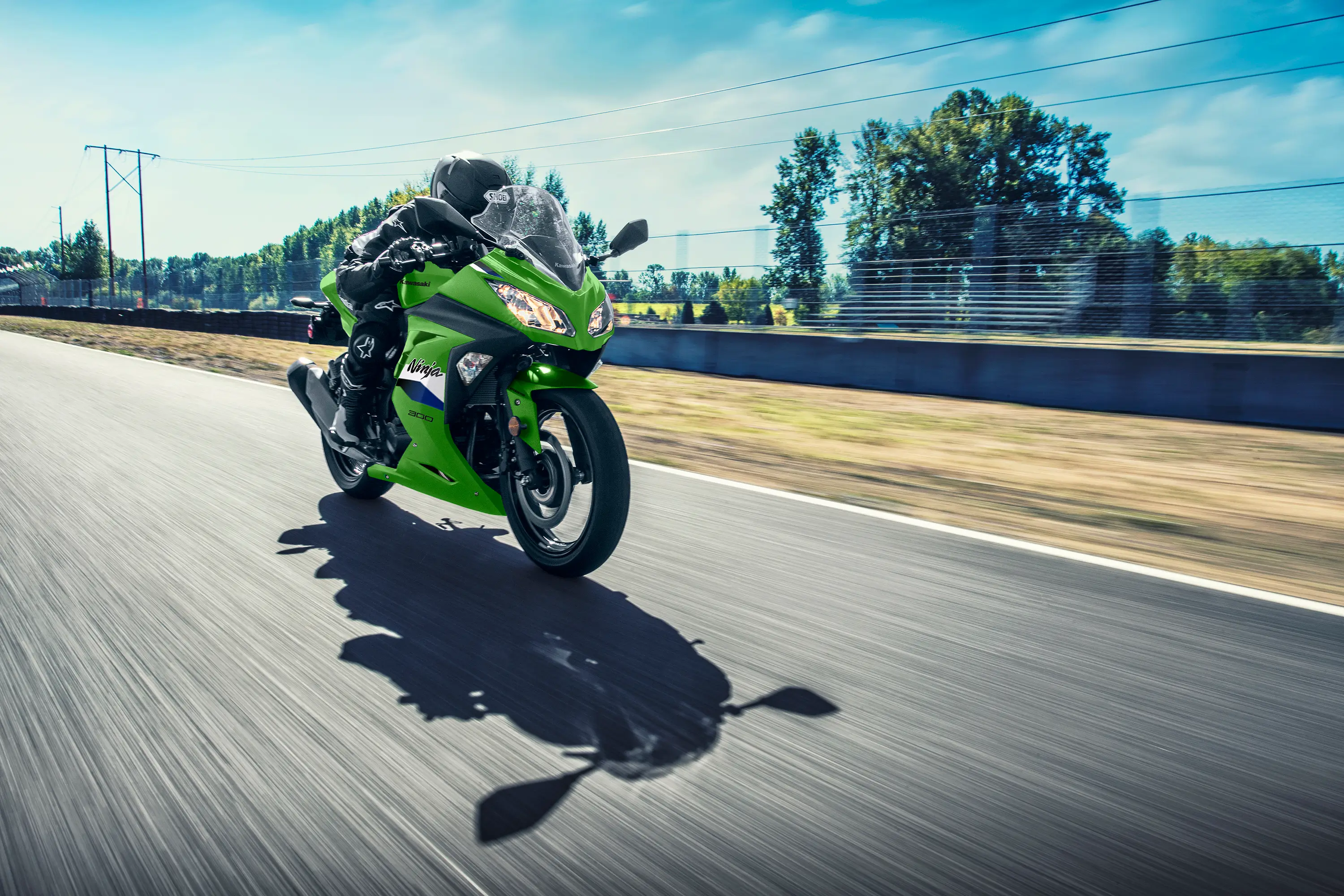 Three-quarter front angle of a person riding a green motorcycle on a track.