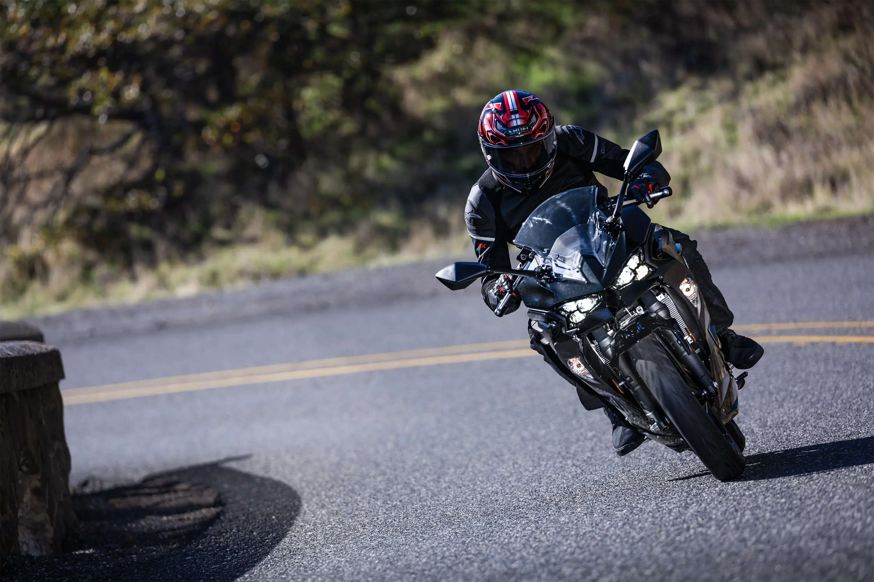 Front angle of a person riding a motorcycle around a bend in a road.