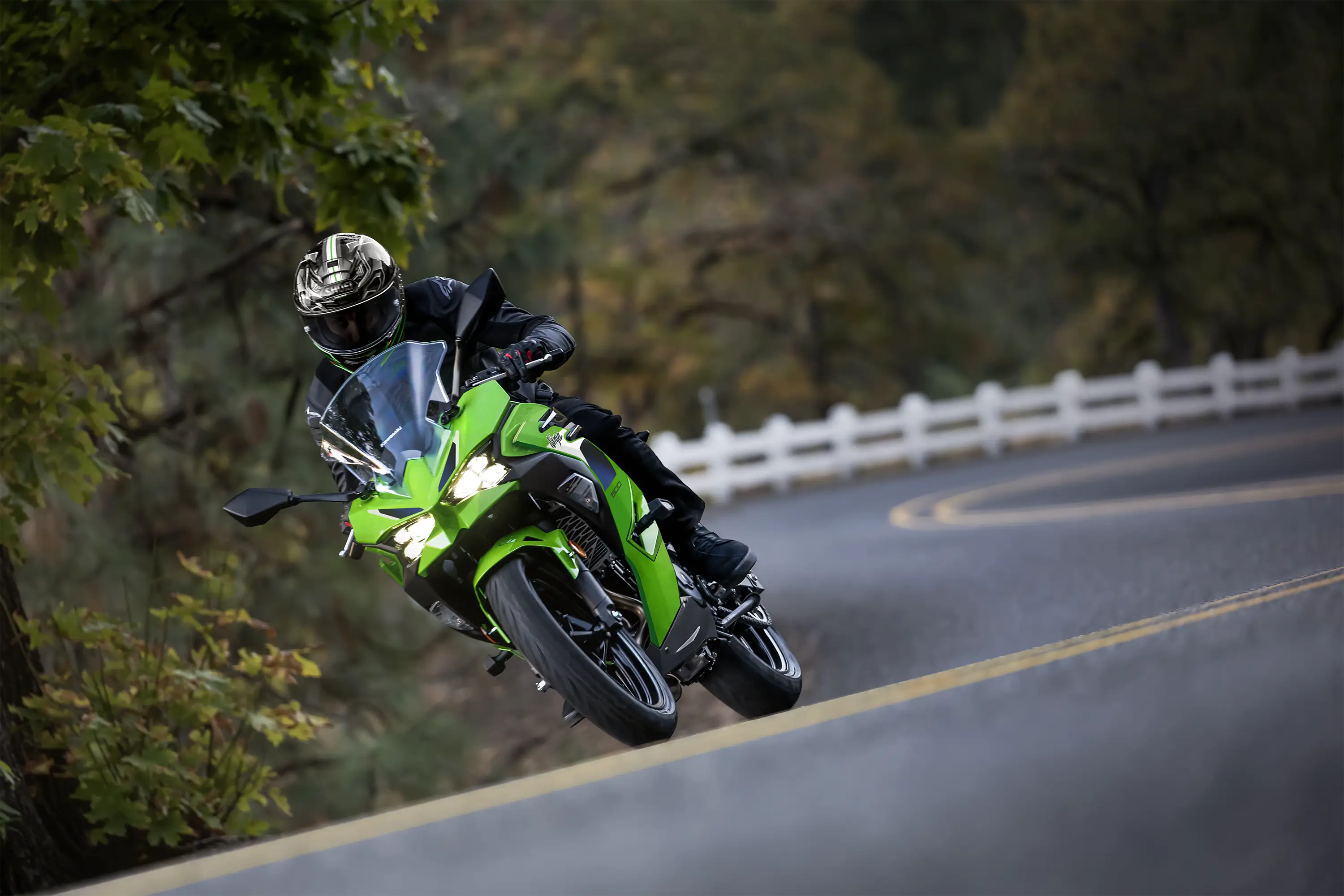 Front angle of a person riding a motorcycle around a bend in a road.