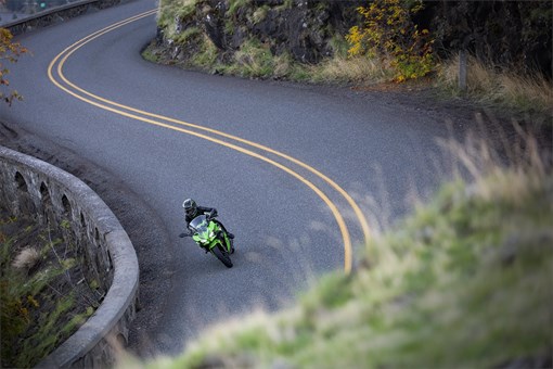 Aerial view of a person riding a motorcycle on a curvy road. opens in a new window