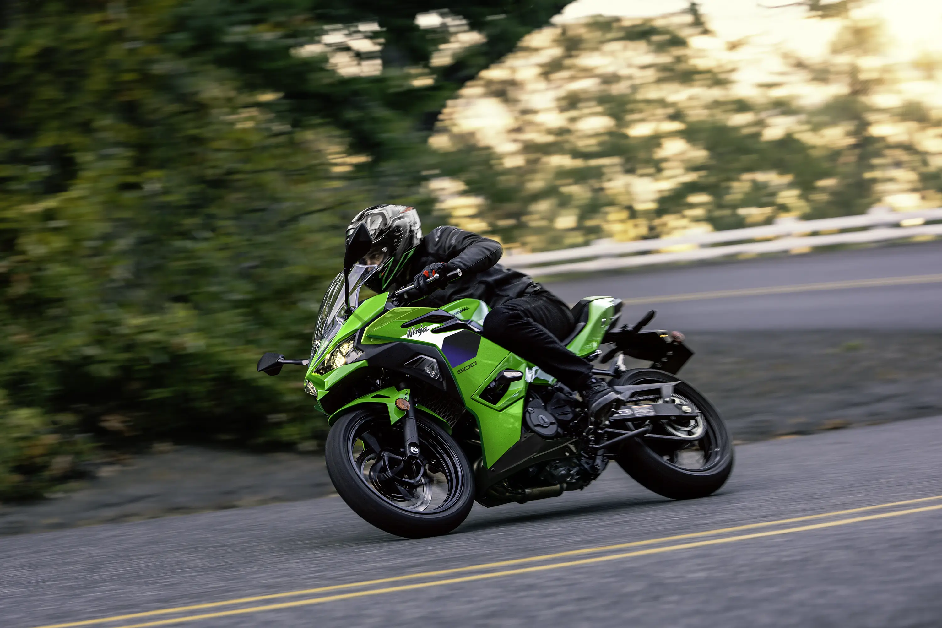 Side angle of a person riding a motorcycle on a road.