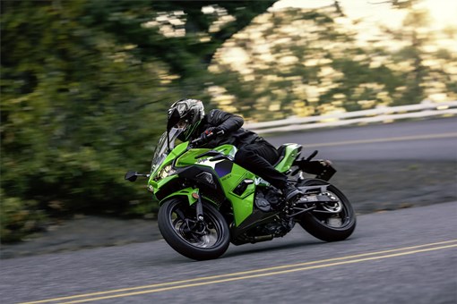 Side angle of a person riding a motorcycle on a road. opens in a new window
