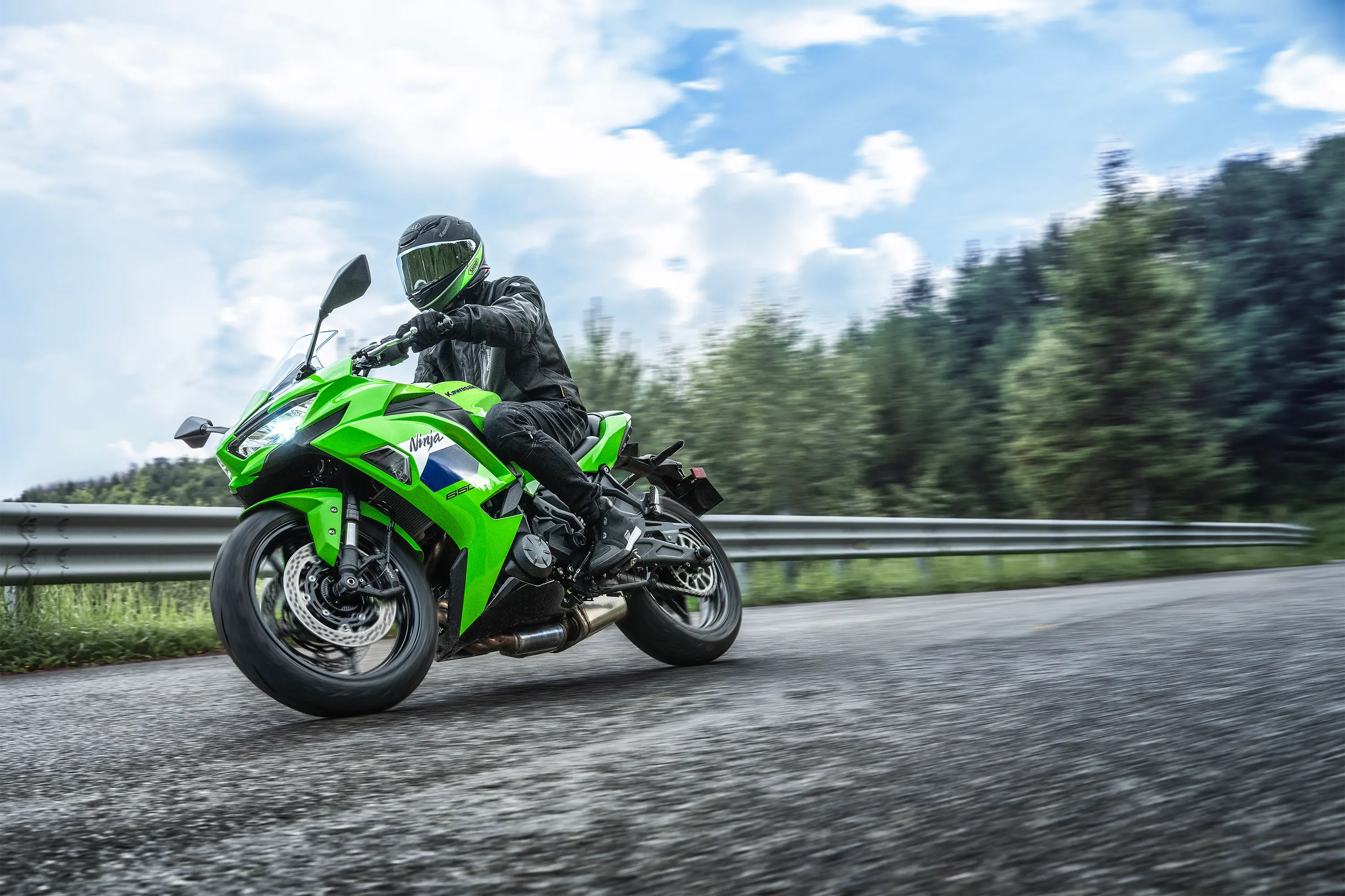 Low front three-quarter angle of a person riding a motorcycle on a highway.