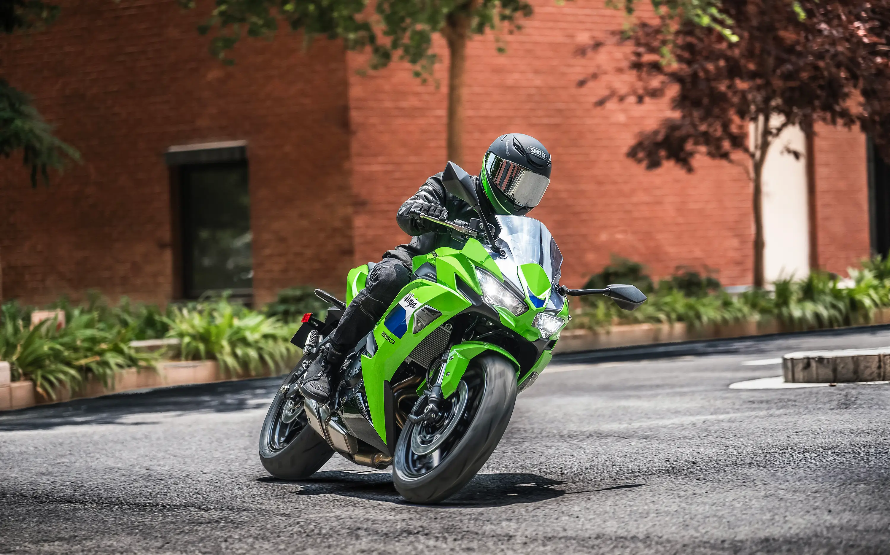 Three-quarter front angle of a person riding a motorcycle on the street.