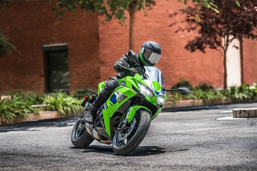 Three-quarter front angle of a person riding a motorcycle on the street. opens in a new window