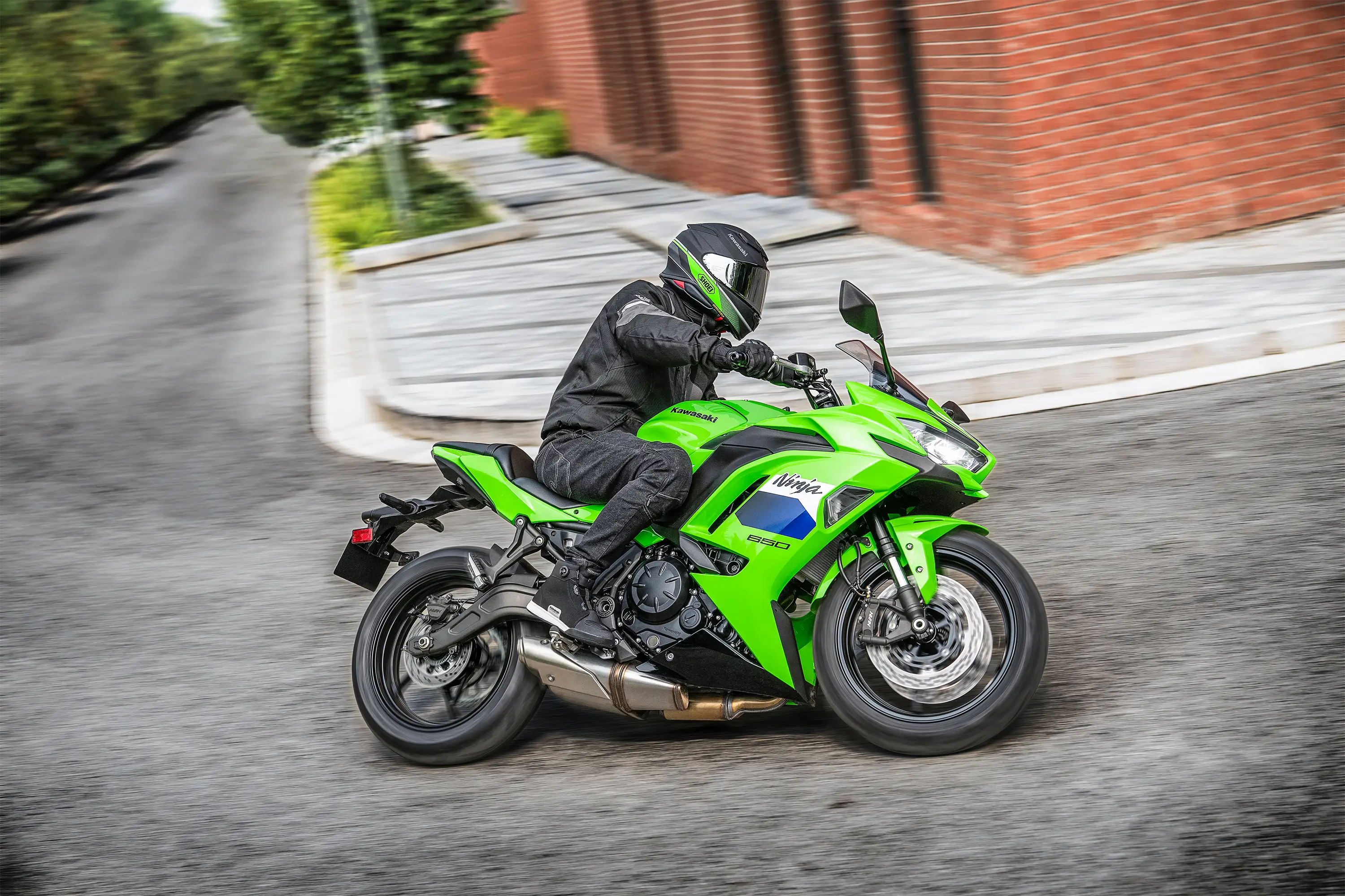 Side angle of a person riding a motorcycle on the street.