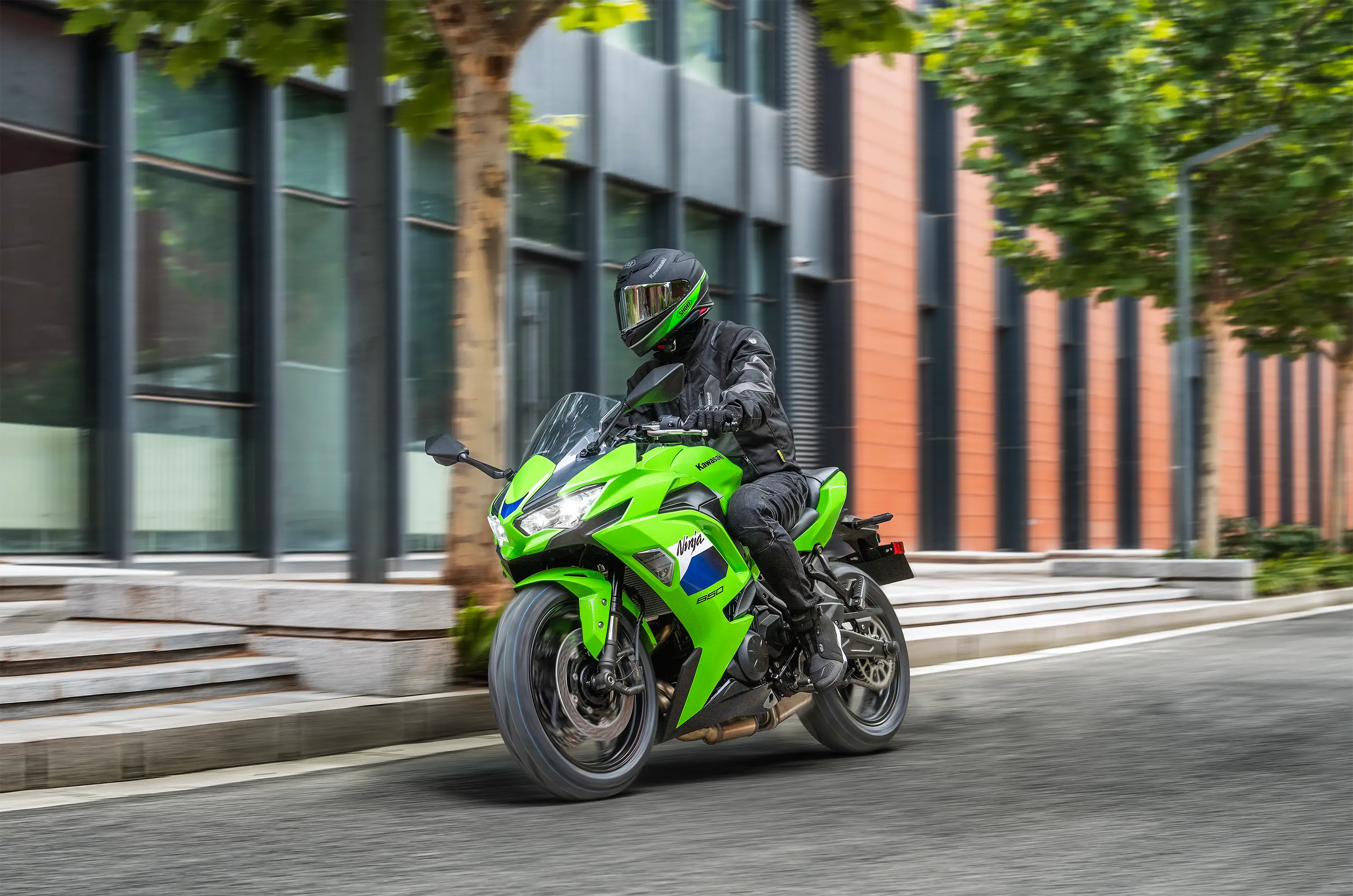 Front three-quarter angle of a person riding a motorcycle on the street.