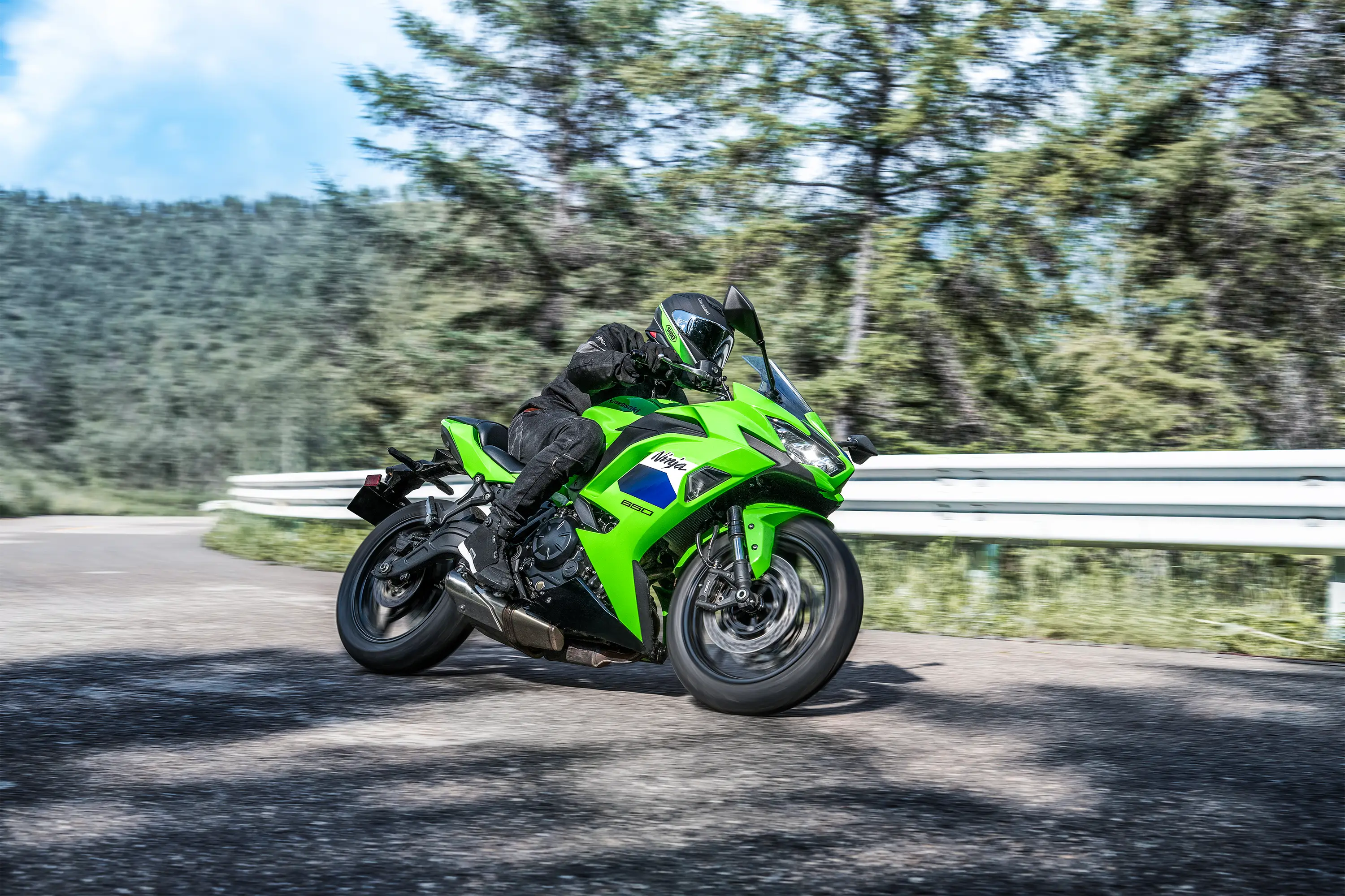 Front three-quarter angle of a person riding a motorcycle on a highway.