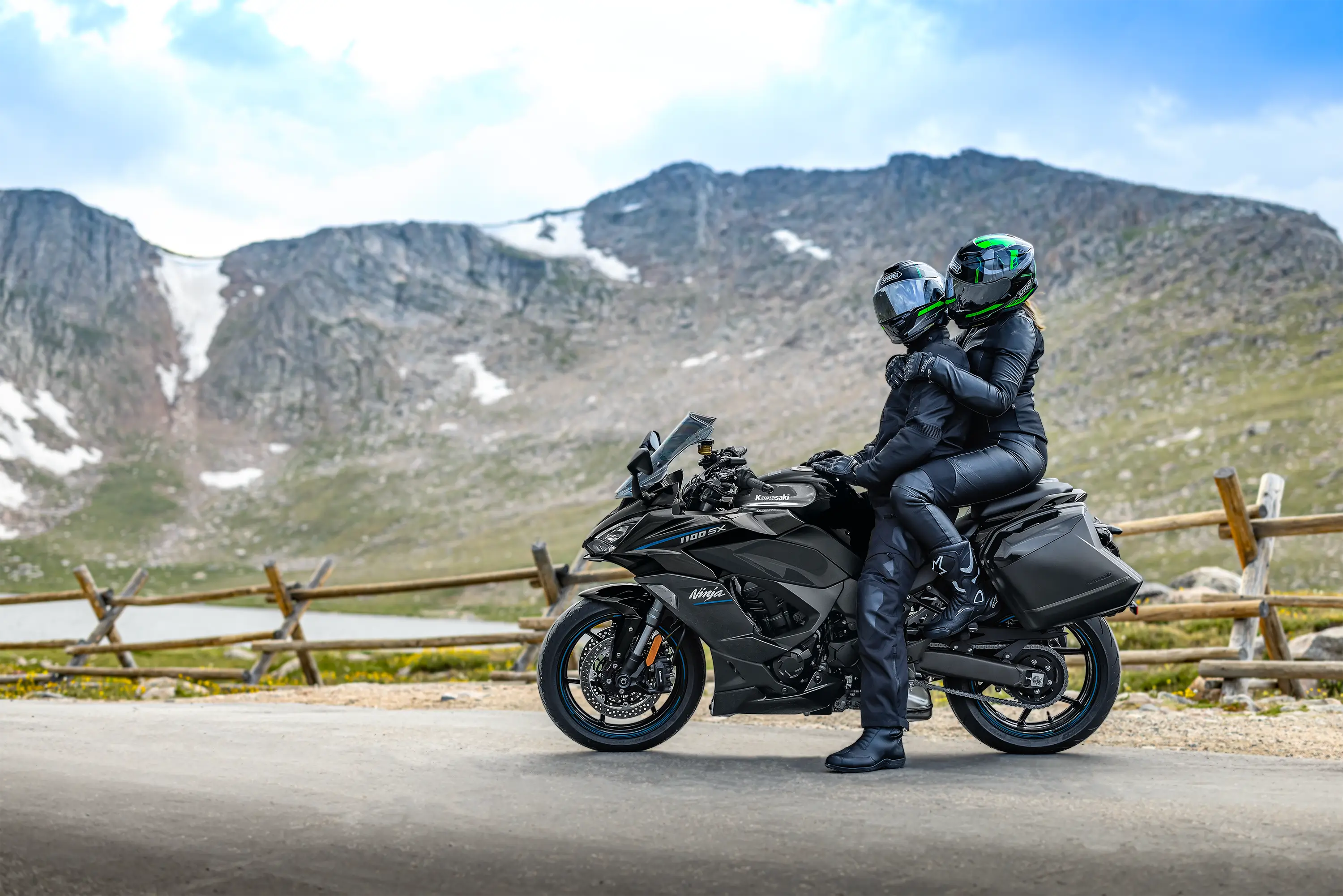 Side angle of a person parked on a motorcycle next to a mountain view.