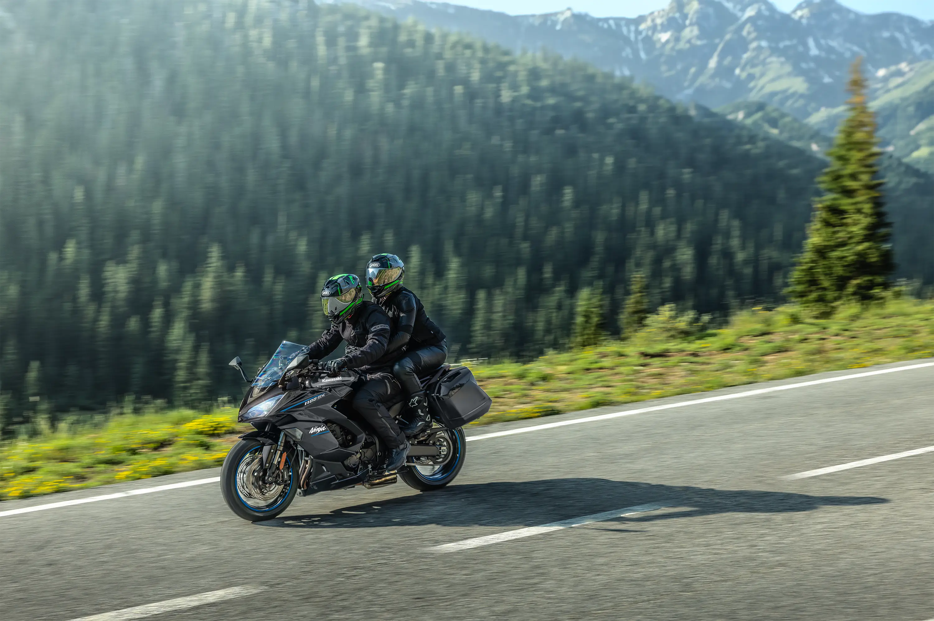Side angle of two people riding a motorcycle on a highway.