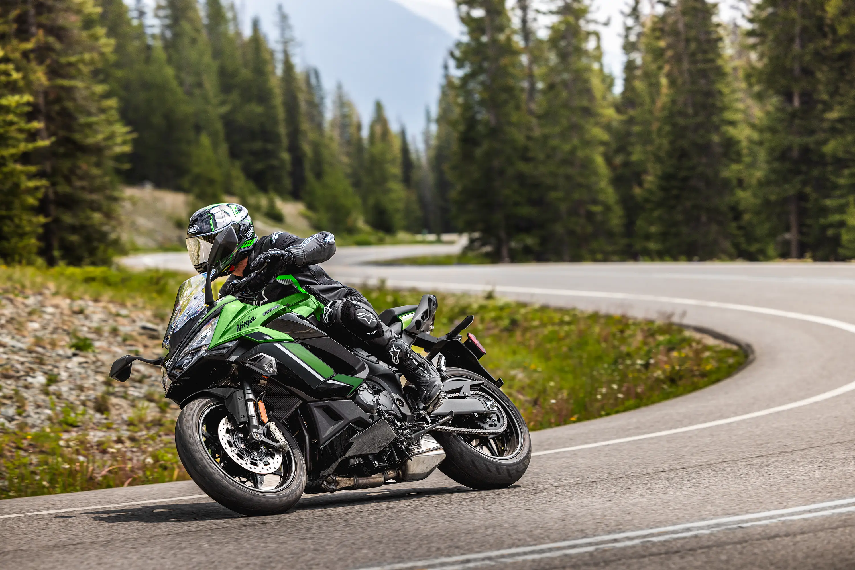 Three-quarter front angle of a person riding a motorcycle on a highway.