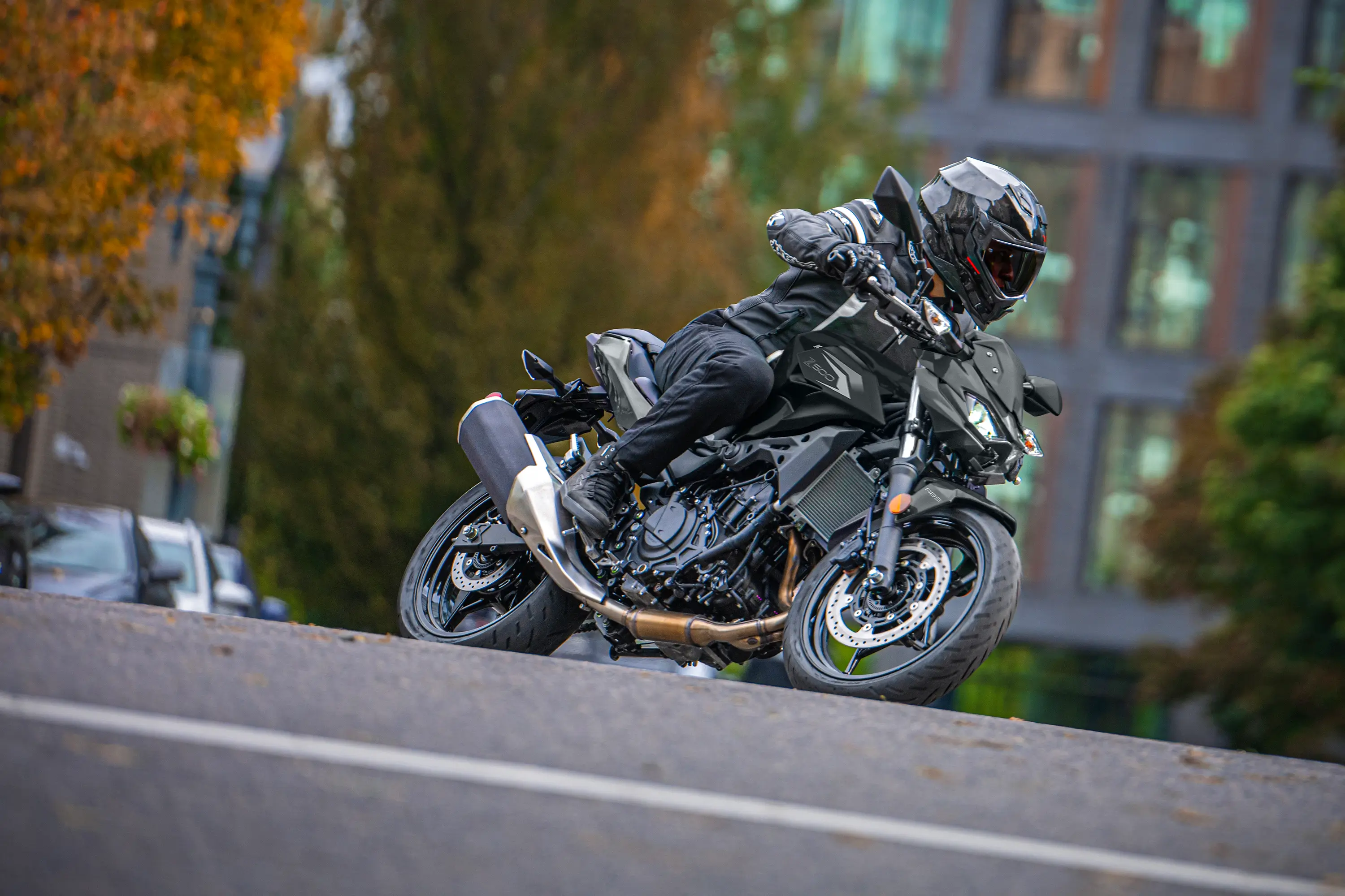 Side angle of a person riding a motorcycle on the street.