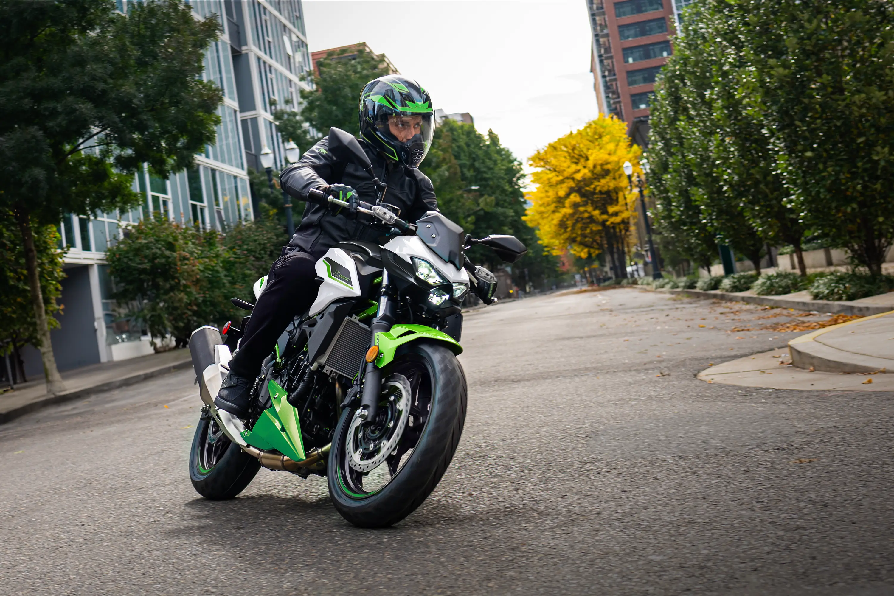 Three-quarter front angle of a person riding a motorcycle on the street.