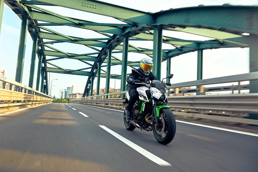 Three-quarter front angle of a person riding a motorcycle on a bridge. opens in a new window