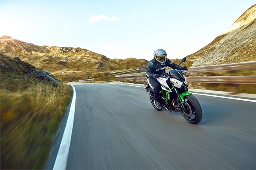 Three-quarter front angle of a person riding a motorcycle on a highway. opens in a new window