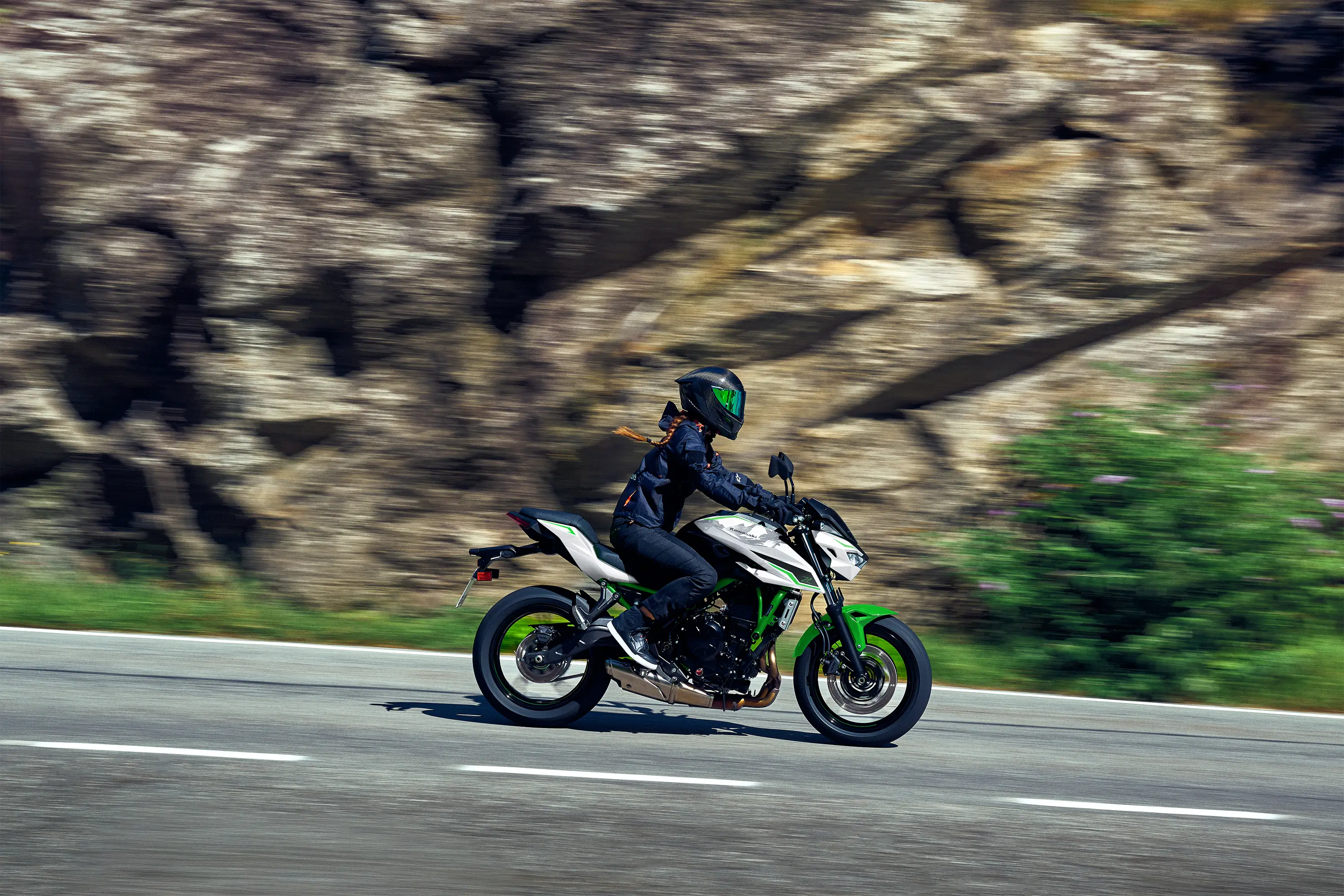 Side angle of a person riding a motorcycle on a highway.