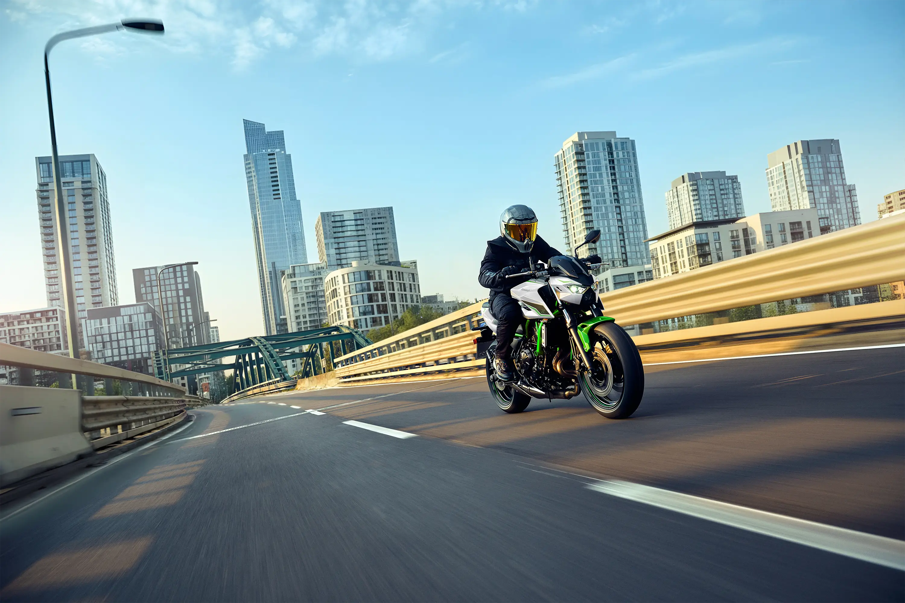 Three-quarter front angle of a person riding a motorcycle on a city highway.