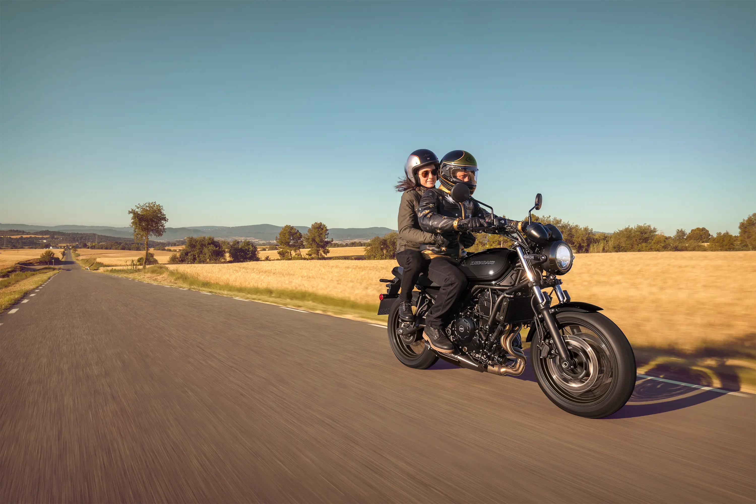 Three-quarter front angle of a people riding a motorcycle on the street.